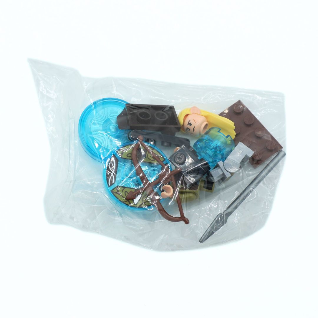 A small toy building-block set sealed in a clear plastic bag, containing a blonde minifigure with a blue torso, brown accessories, and a gray sword on a white background.