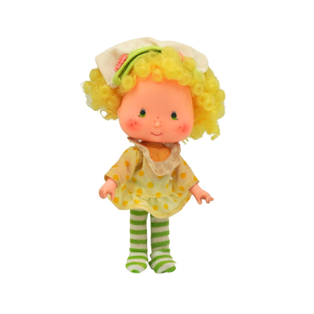 Toy doll with yellow hair, polka dot dress, and green striped socks on a white background