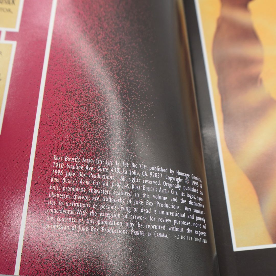 A close-up of an open book or printed publication showing a dark red page with small white text and a partial photo of a person in the upper right corner.
