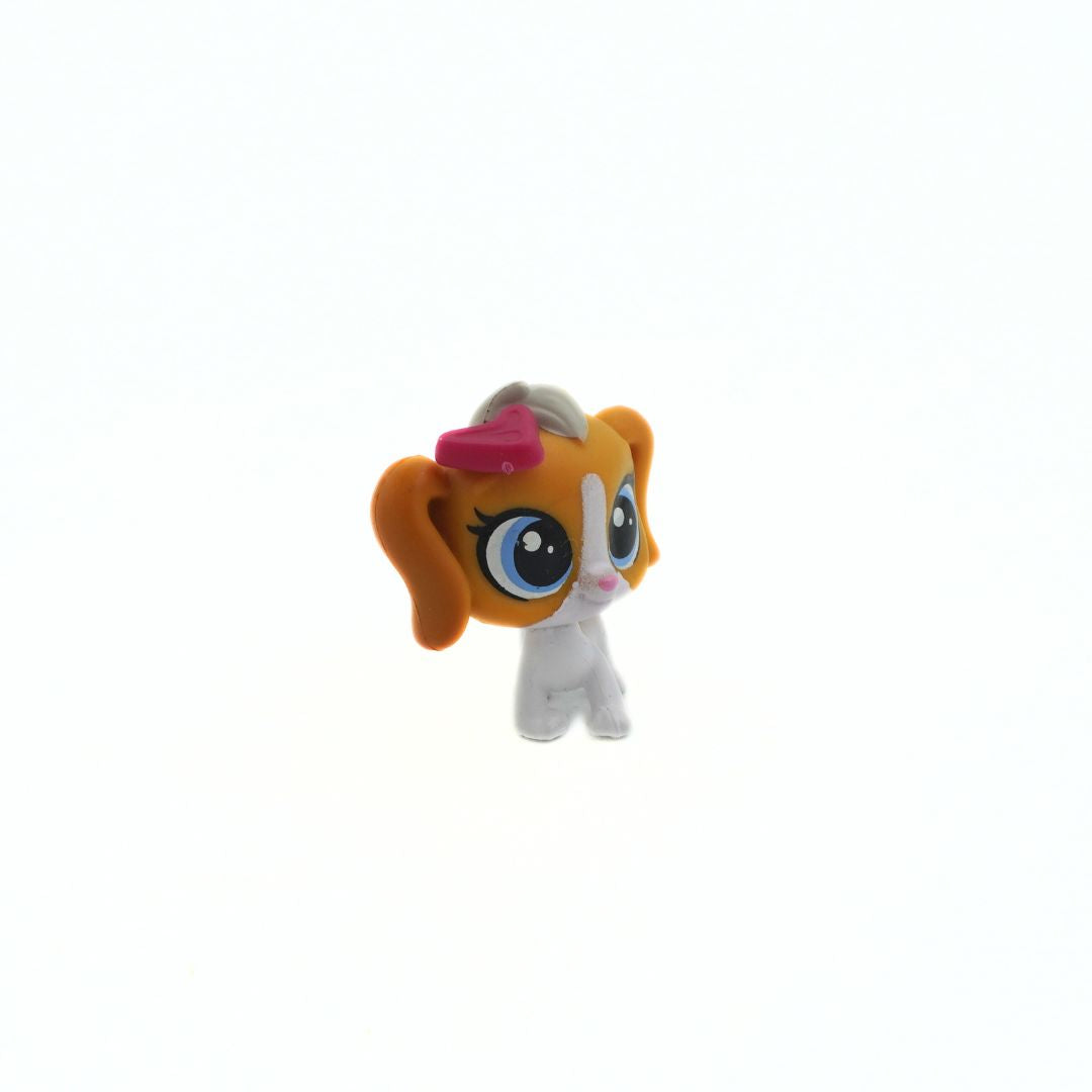 Small toy figure with orange hair and a pink bow on a white background