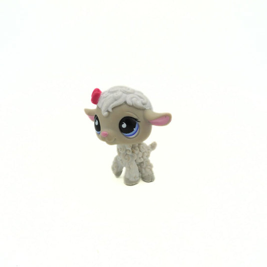 Small toy lamb with a pink bow on a white background