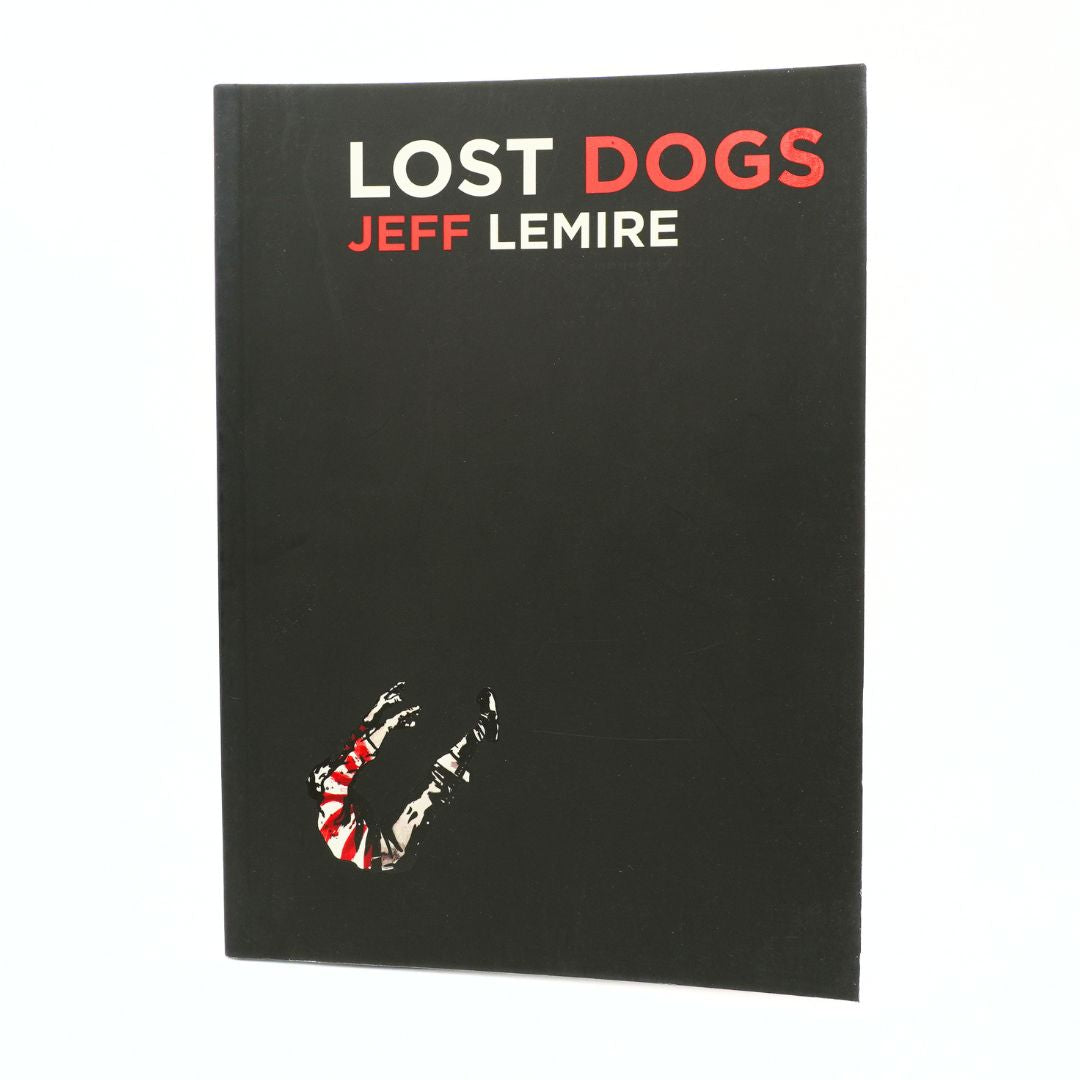 A black book or notebook titled 'LOST DOGS' by Jeff Lemire, featuring bold red and white text at the top and a small graphic near the bottom, shown against a plain white background.