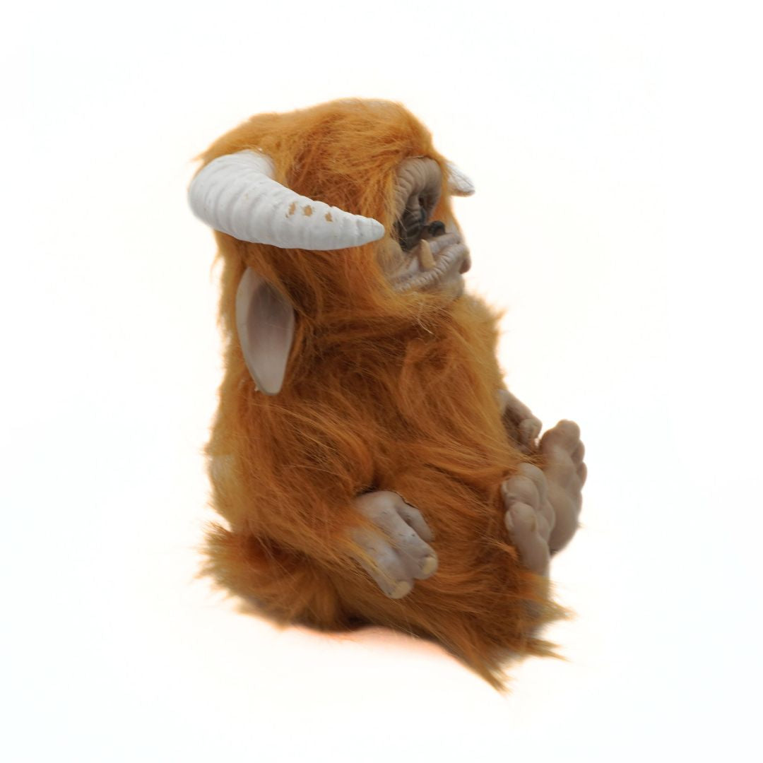 Solid furry toy resembling a creature with orange fur and white horns on a white background