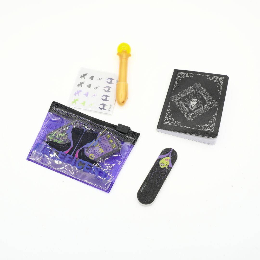 A Halloween-themed miniature accessory set on a white background, including a small purple zipper pouch with a spider-themed design, a black miniature card with a skull pattern, a small black rectangular item with a spider graphic, a yellow-and-black miniature tool, and a sheet of small black stickers.
