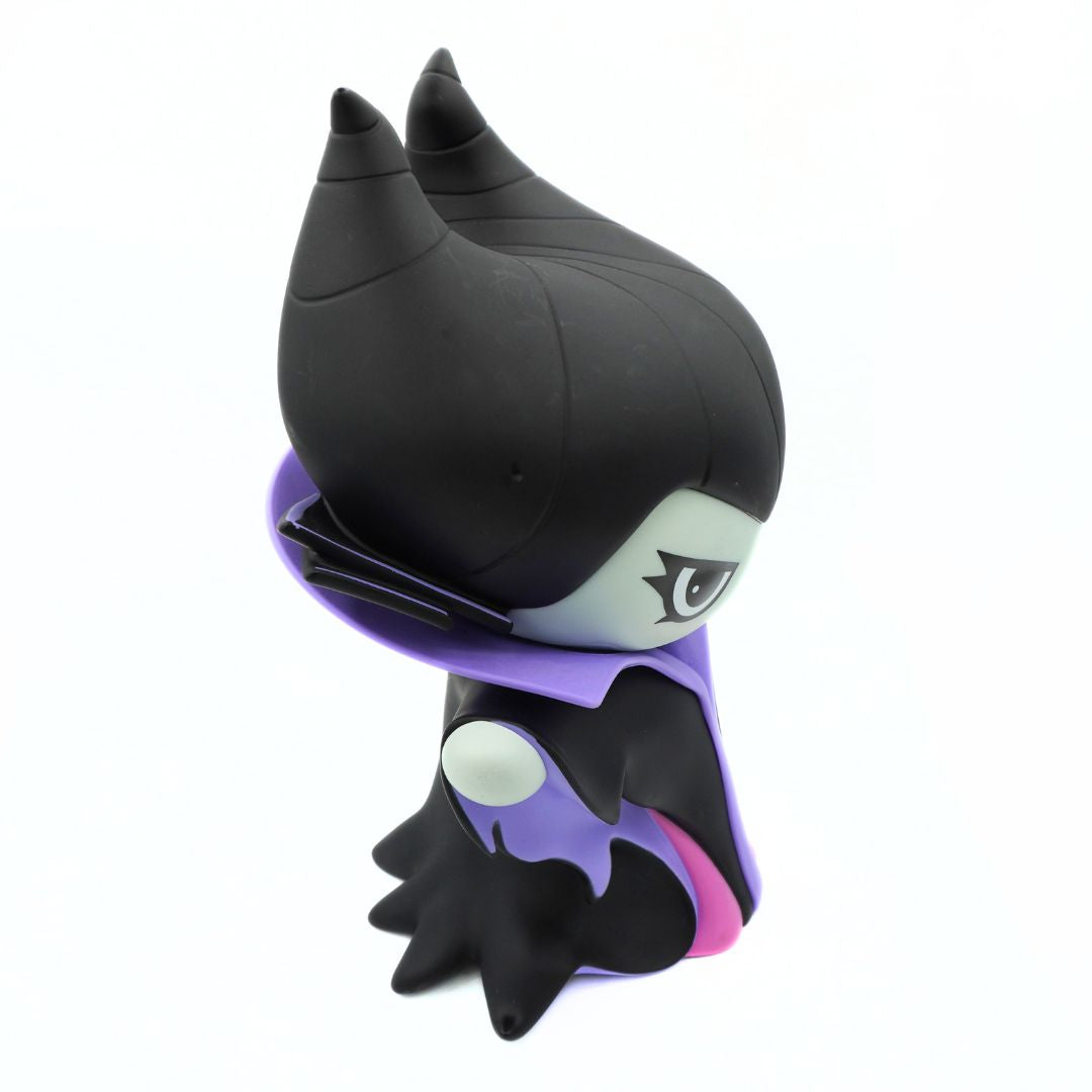 A green figurine wearing a purple and black jacket and black hat, holding a gold rod