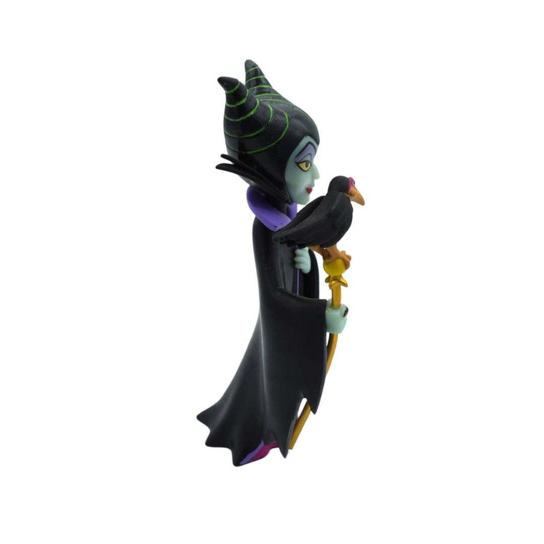 A collectible figurine of Maleficent from Disney's Sleeping Beauty, shown in profile holding a raven on a golden staff, set against a plain white background.