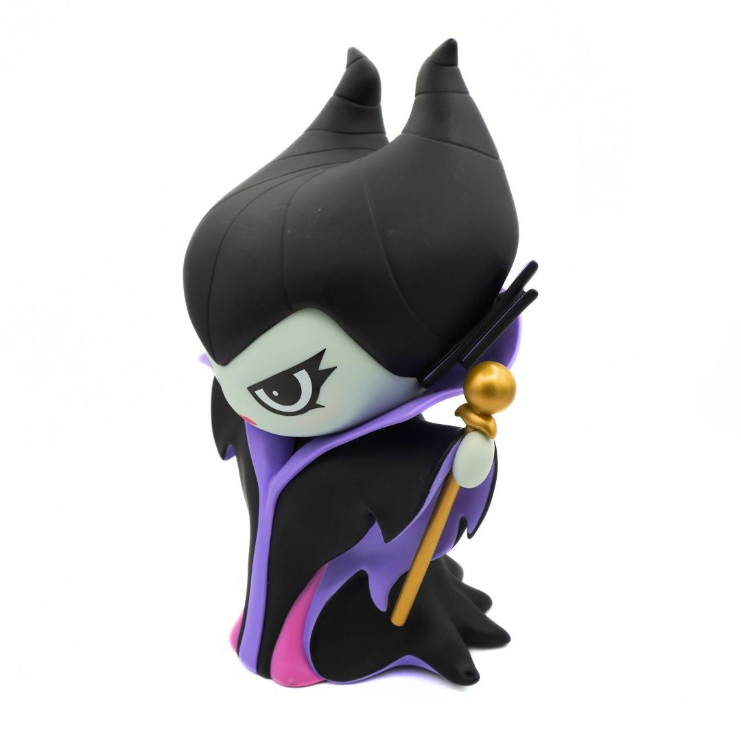 A green figurine wearing a purple and black jacket and black hat, holding a gold rod