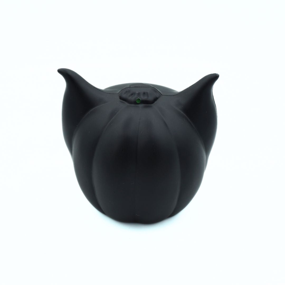 A matte black cat-shaped pouf or small decorative object with pointed ears and a small green accent at the top, shown on a plain white background.
