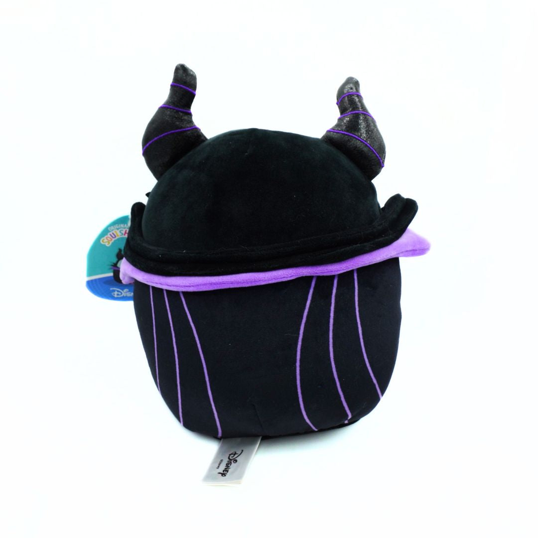 A plush toy shaped like a horned character, primarily black with purple trim and vertical purple pinstripes, photographed on a white background. A blue and red hangtag is attached on the left side, and a small white brand tag is visible at the bottom.