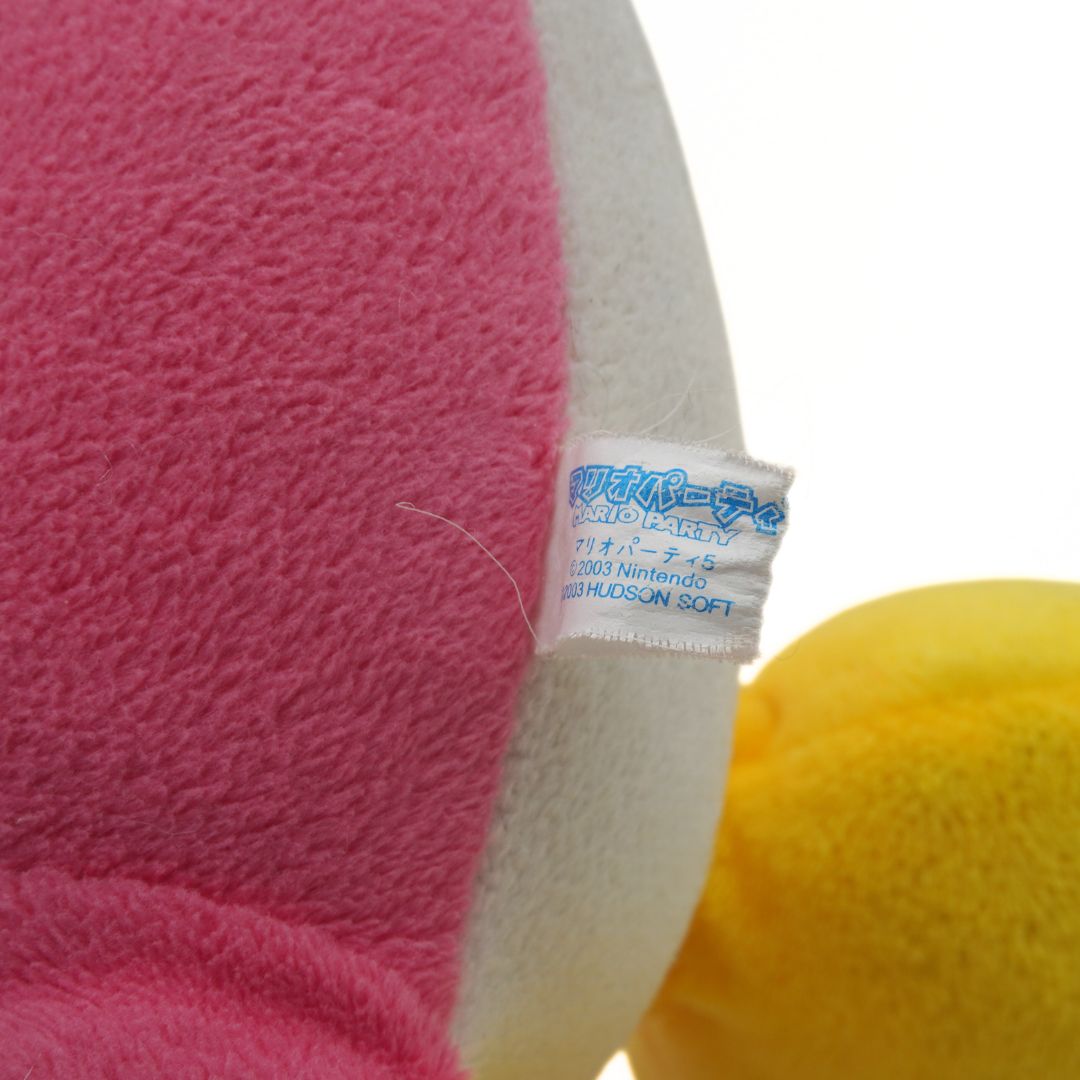Close-up of a plush toy with a label on a pink and yellow background