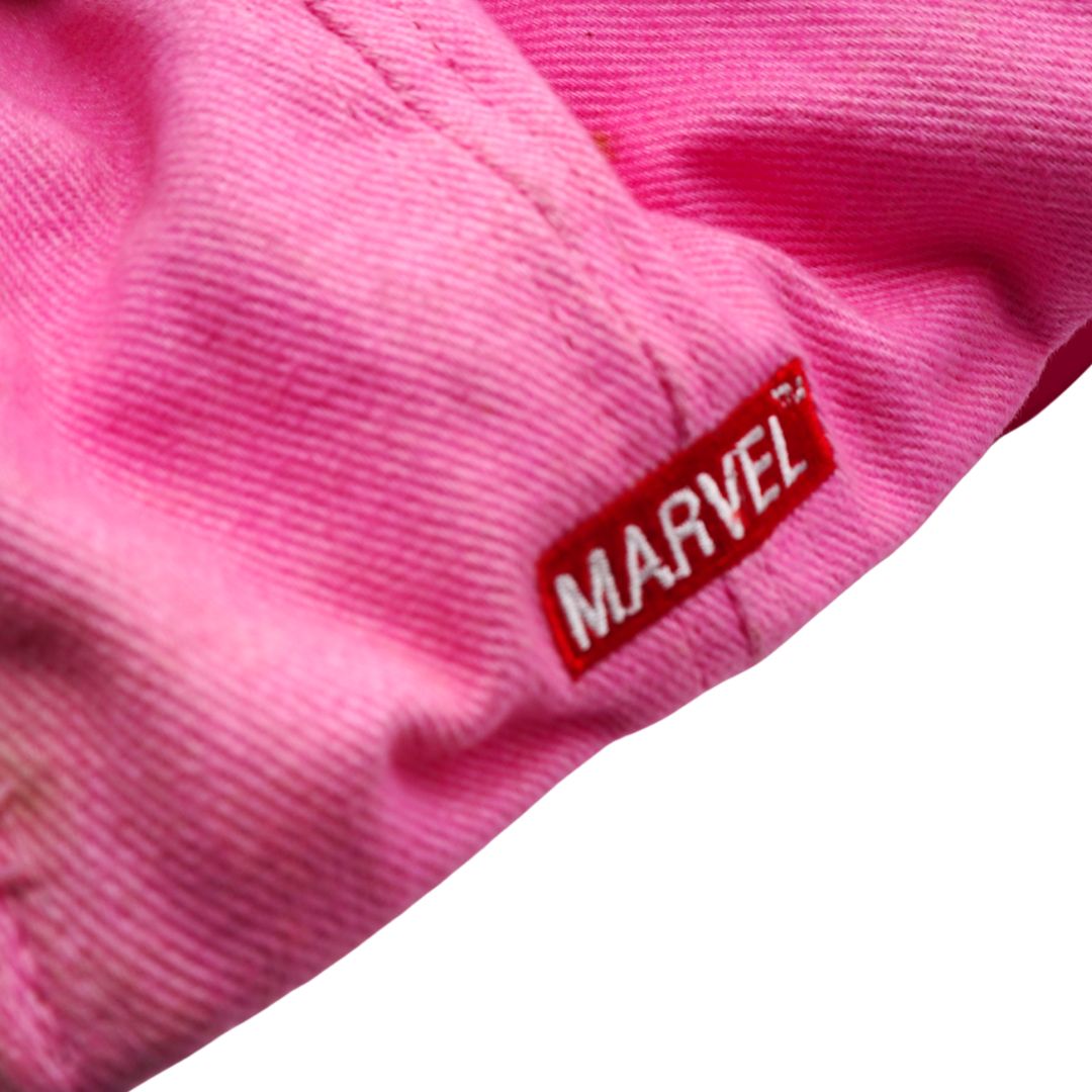 Close-up of a pink woven fabric with a red rectangular Marvel logo patch on the right side, against a white background.