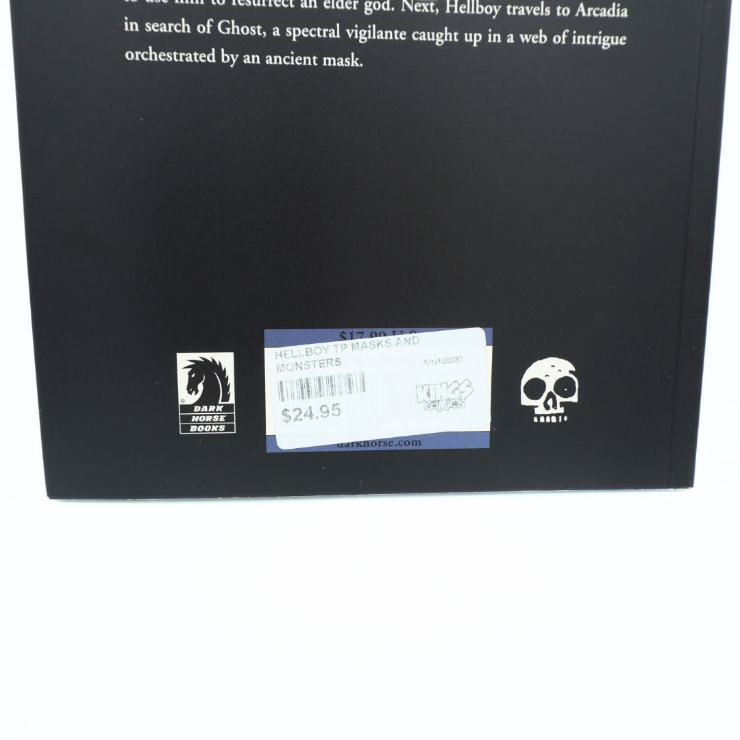 Back cover of a book or box in black, showing partial white text at the top, a central white price sticker, a black horse logo on the left, and a white skull logo on the right, photographed against a white background.
