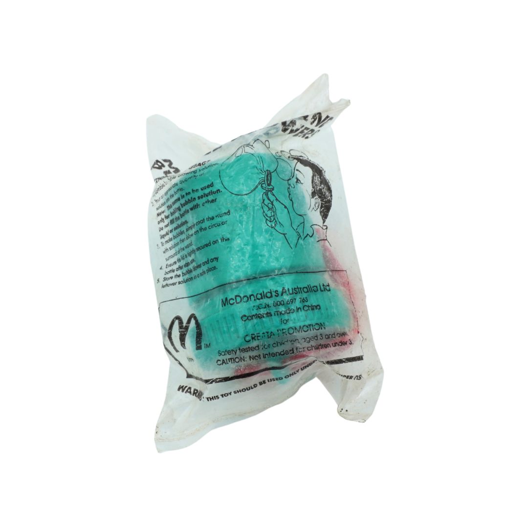 A sealed plastic bag containing a McDonald's Australia limited edition toy, featuring a turquoise blue figure with a black hair tuft and black printed text and logo.