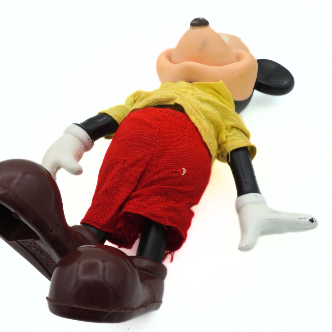 Toy figure of a character in red shorts and yellow shirt on a white background