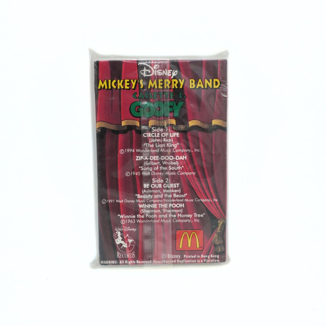 A Disney Mickey's Merry Band cassette tape in its original plastic shrink-wrap packaging, showing the back cover with track listings and a McDonald's logo.