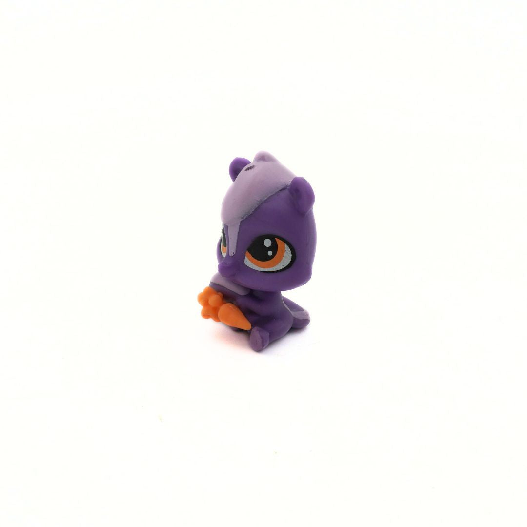 Small purple toy figure with orange carrot on a white background