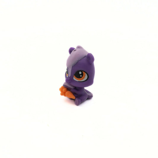 Small purple toy figure with orange carrot on a white background