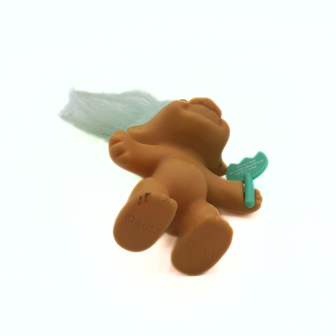 Brown troll doll with green accents on a white background