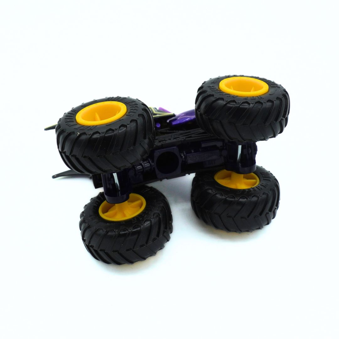 A toy monster truck shown upside down on a plain white background. The truck has four large black tires with bright yellow rims and a purple body.