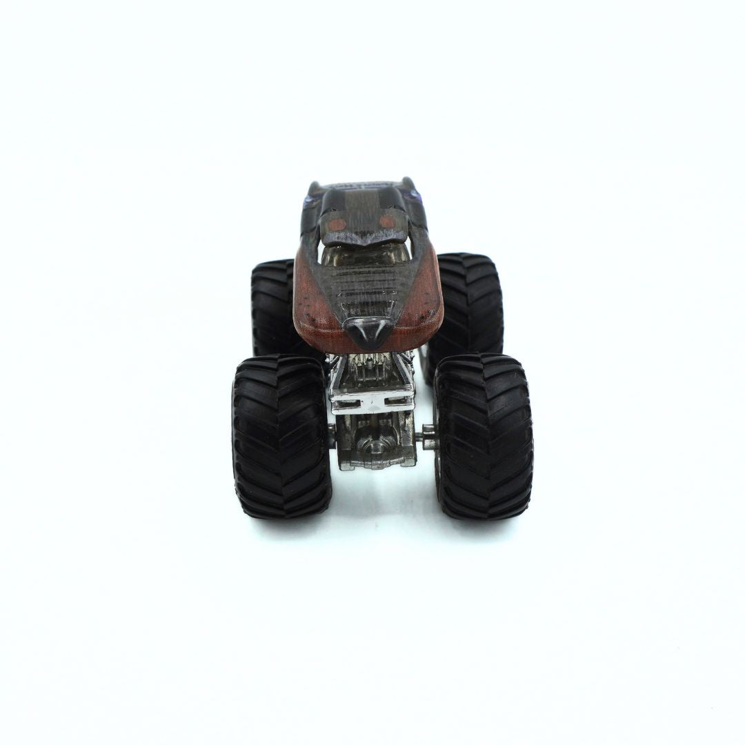 A small monster truck with large black off-road tires, a dark gray body, and a brown hood, photographed from the rear on a plain white background.