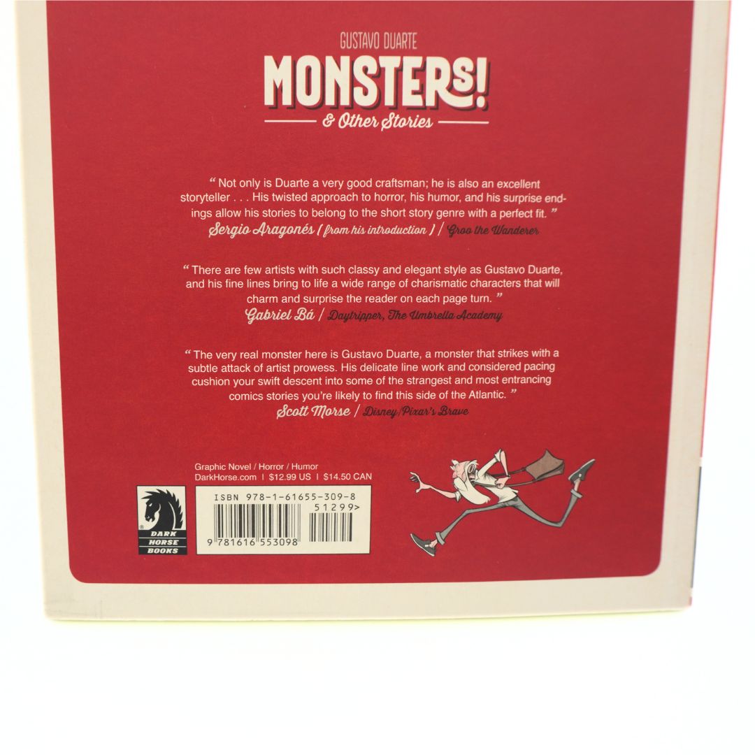 The back cover of the book 'Monsters! & Other stories' by Gustavo Duarte, featuring a solid red background with white text, a barcode, and a cartoon illustration of a white rabbit with a red bow and arrow.