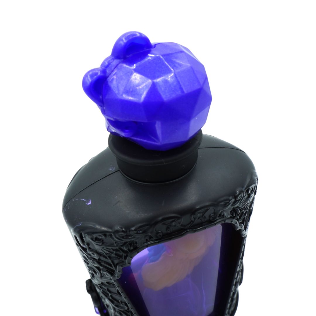 A close-up of a black decorative bottle with a faceted purple cap shaped like a stylized head, shown against a plain white background.