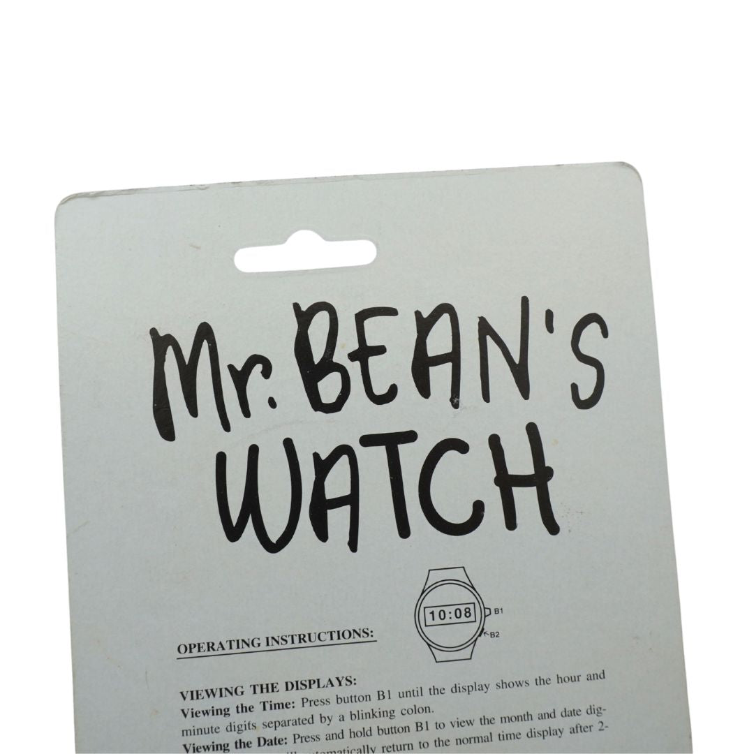 A novelty watch in its original packaging, featuring a round analog clock face with a blinking black coin at the center and bold black text reading 'Mr. BEAN'S WATCH' on a light gray backing card.