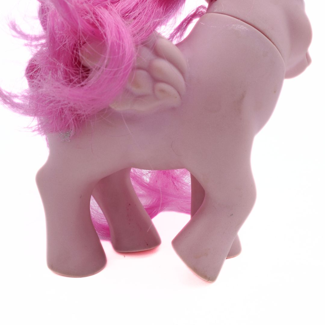 Close-up of a pink toy horse with bright pink hair on a white background