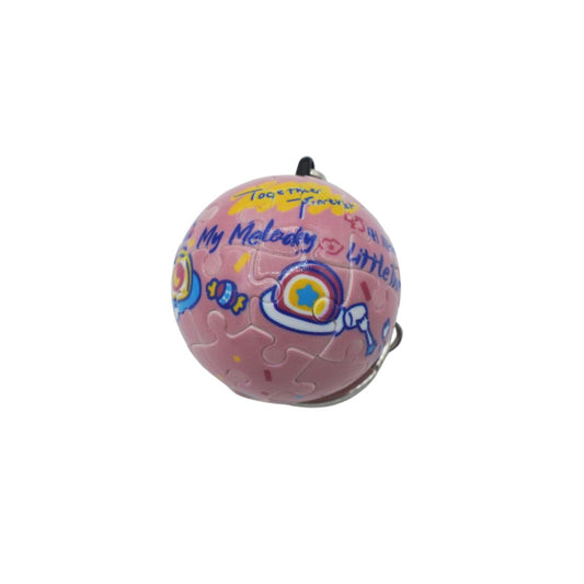 A pink jigsaw puzzle ball charm with colorful painted details, including the words 'Togetherness', 'My Melody', and 'little', shown on a plain white background.