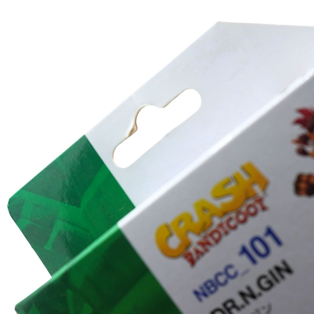 Close-up of a retail package corner showing a white cardboard header with a hanging tab, green side panel, yellow 'CRASH BANDICOOT' text