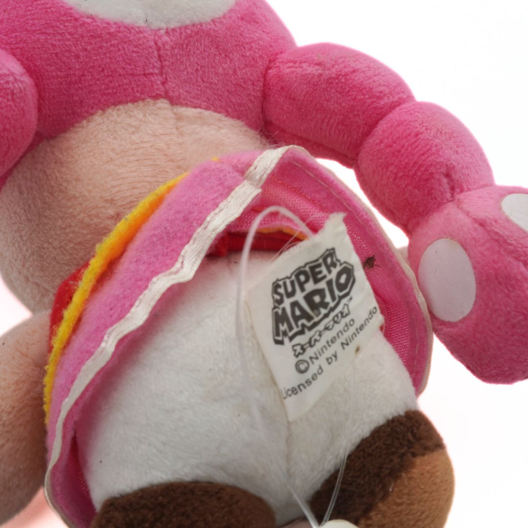 Close-up of a pink plush toy with a tag, featuring Super Mario branding.