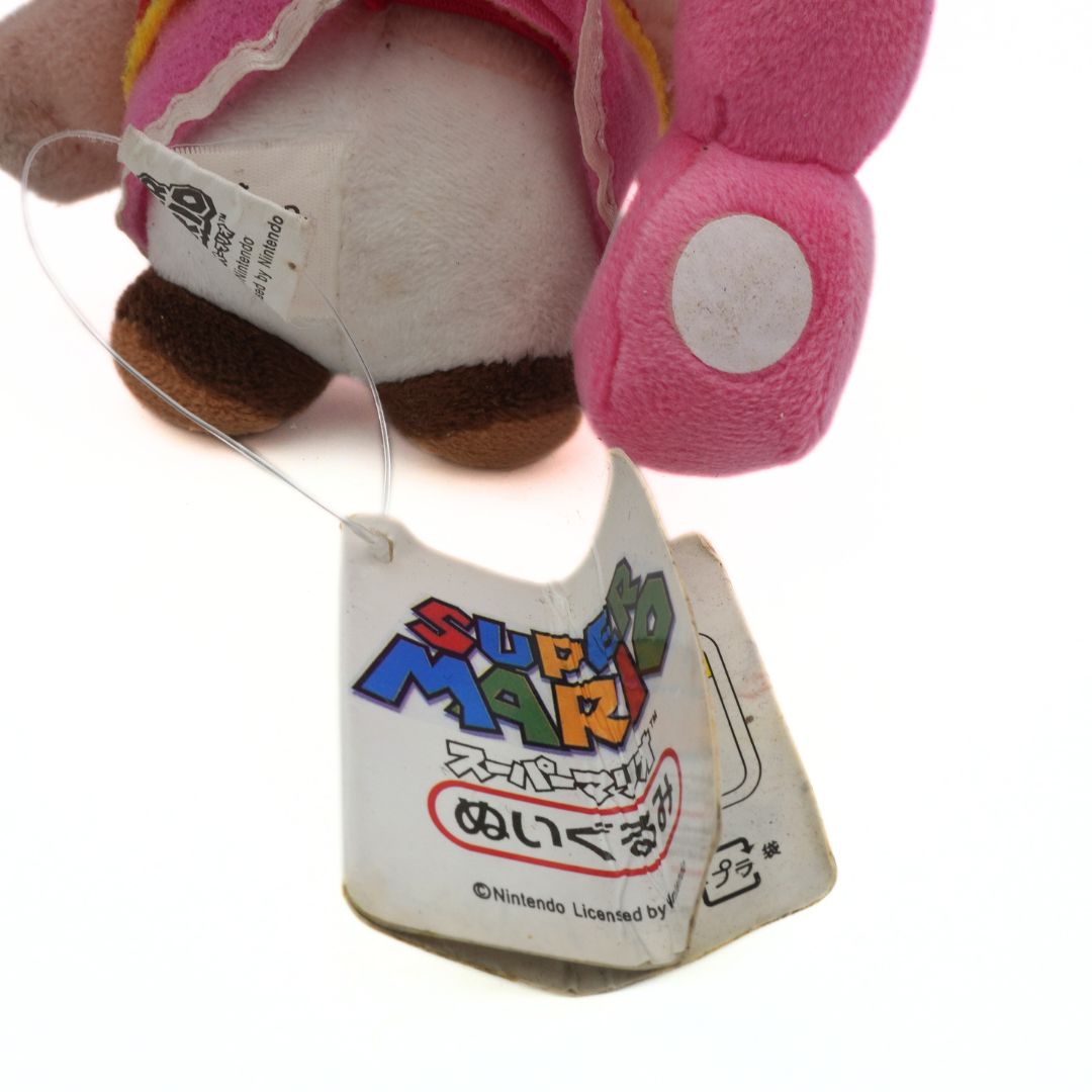 Plush toy with a tag featuring 'Super Mario' branding on a white background