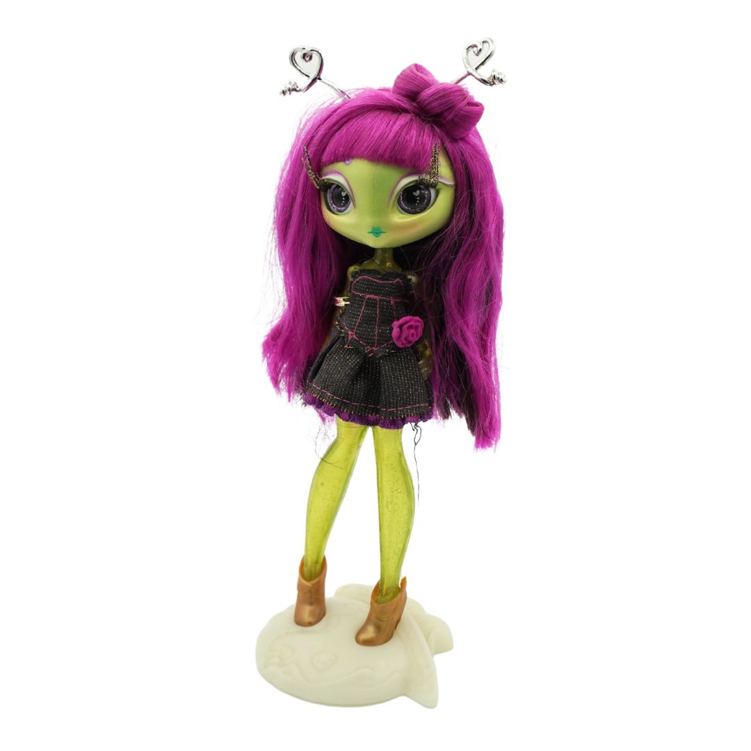 A Novi Star doll with green legs and purple hair, wearing a dark denim dress and standing on a cream coloured stand