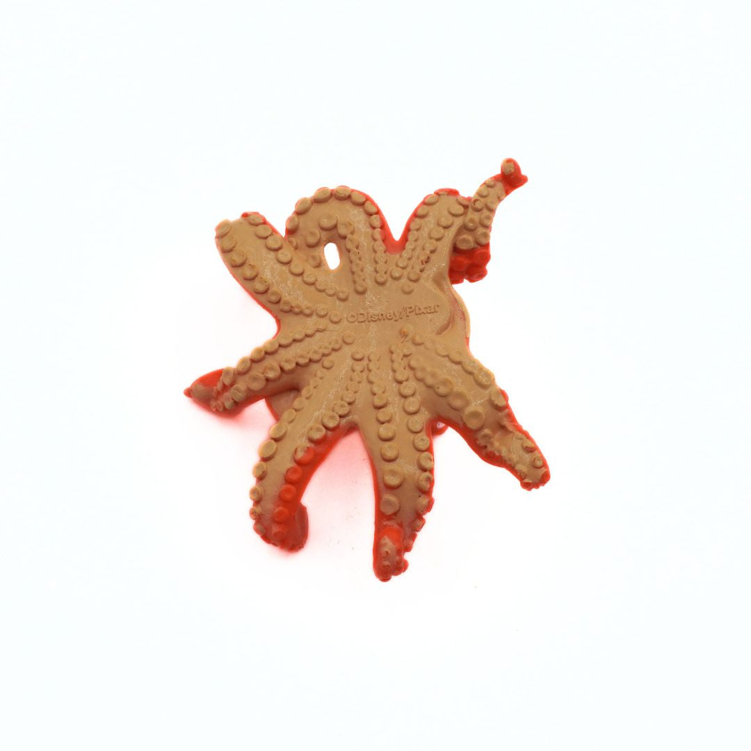 Plastic toy shaped like an octopus with red accents on a white background
