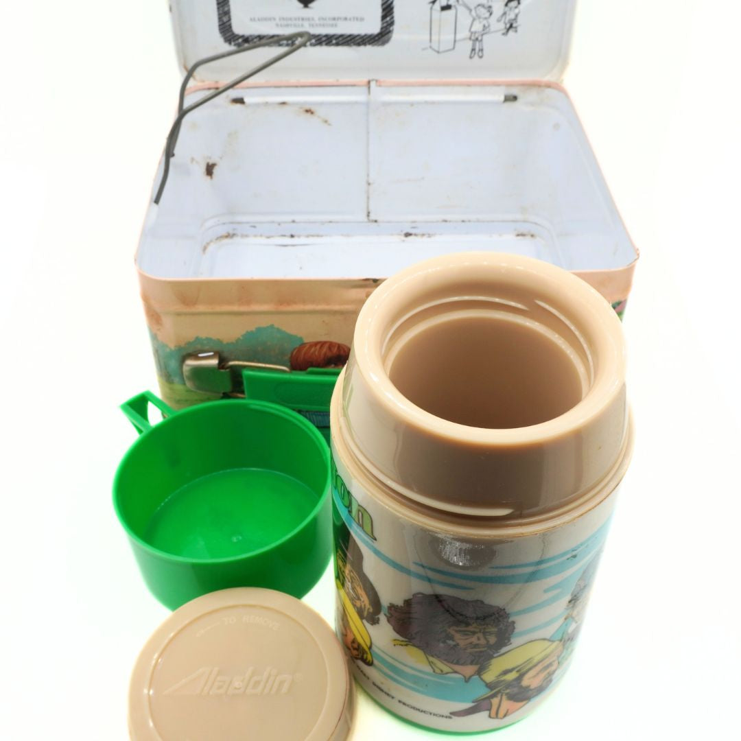 Children's thermos and green cup with cartoon design in front of a vintage lunchbox.