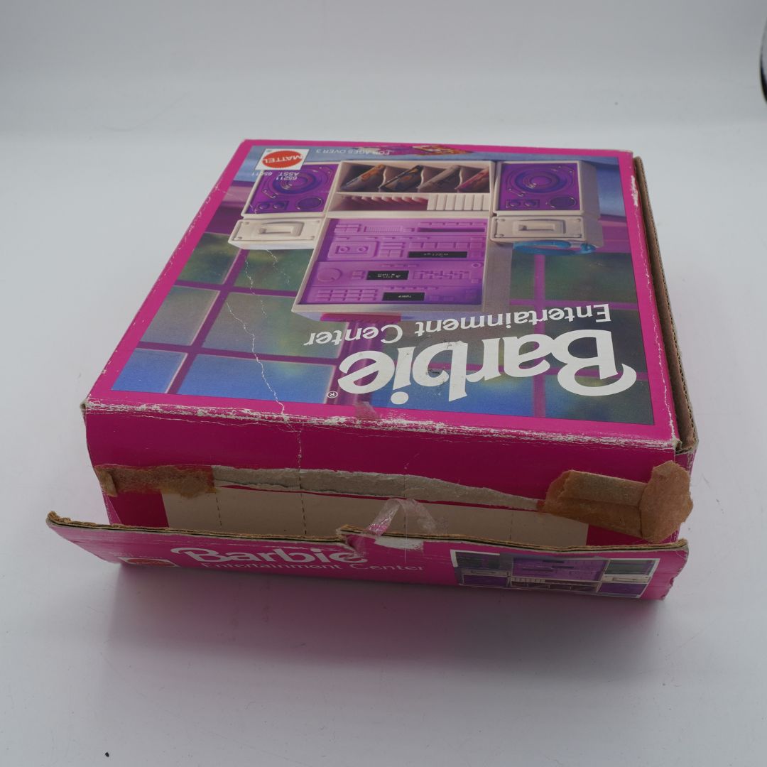 Vintage Barbie Entertainment Center toy box in pink cardboard packaging, showing a purple cassette-deck style toy illustration on the lid, photographed on a plain light background.
