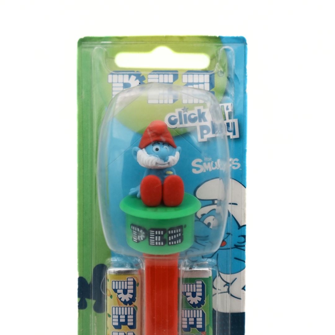 Closeup of the top part of a Click N Play Papa Smurf Pez Dispenser showing Papa Smurf sitting on a green Pez branded platform