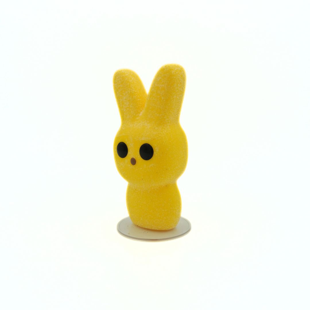 Yellow vinyl toy with rabbit ears on a white background