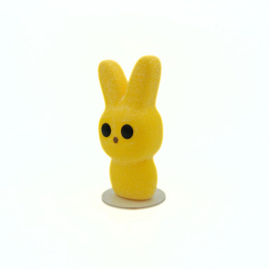 Yellow vinyl toy with rabbit ears on a white background