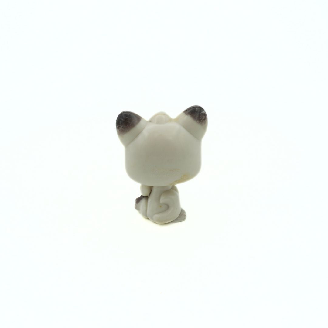 Small white cat figurine with black accents on a white background