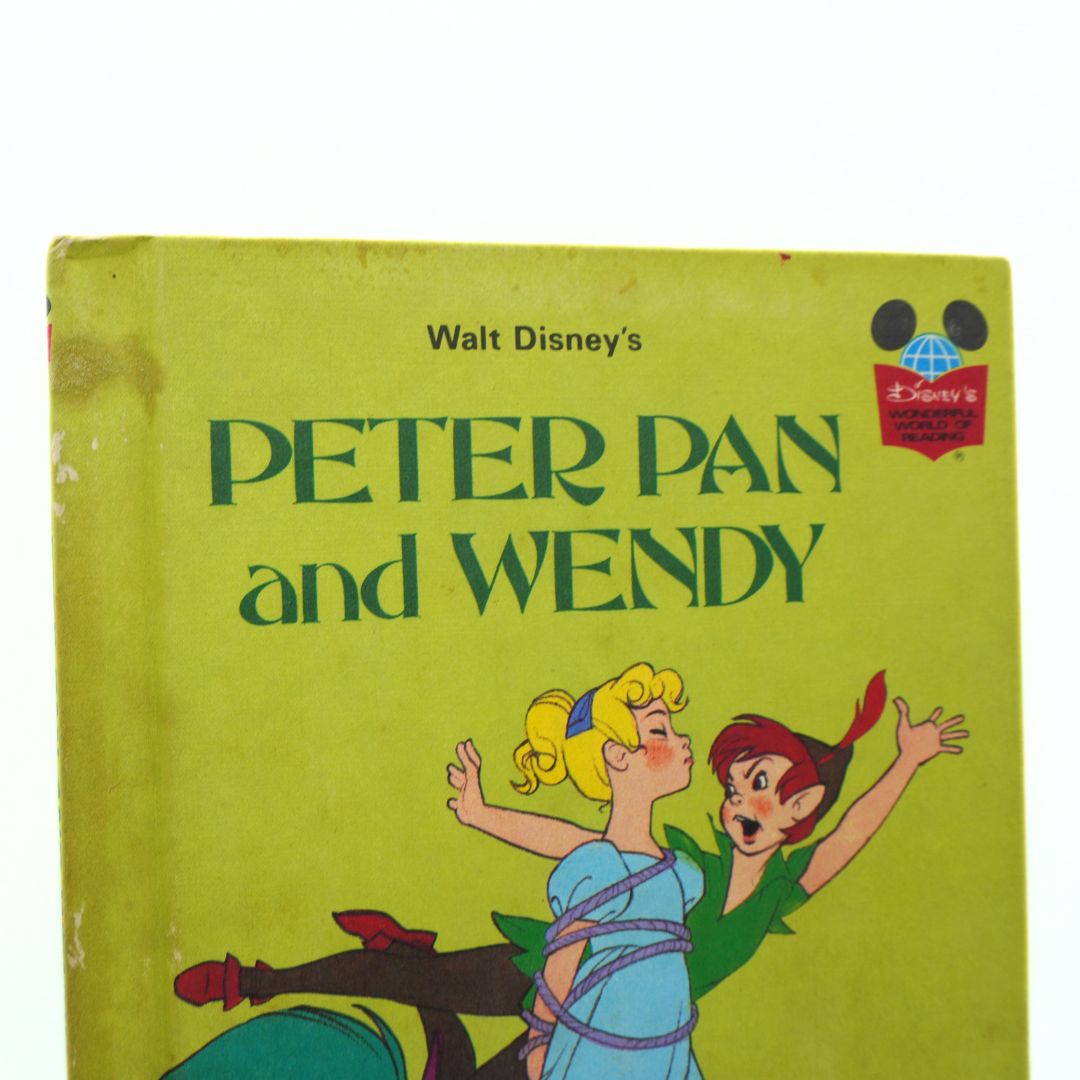 Vintage book cover of 'Peter Pan and Wendy' by Walt Disney with cartoon characters on a green background.