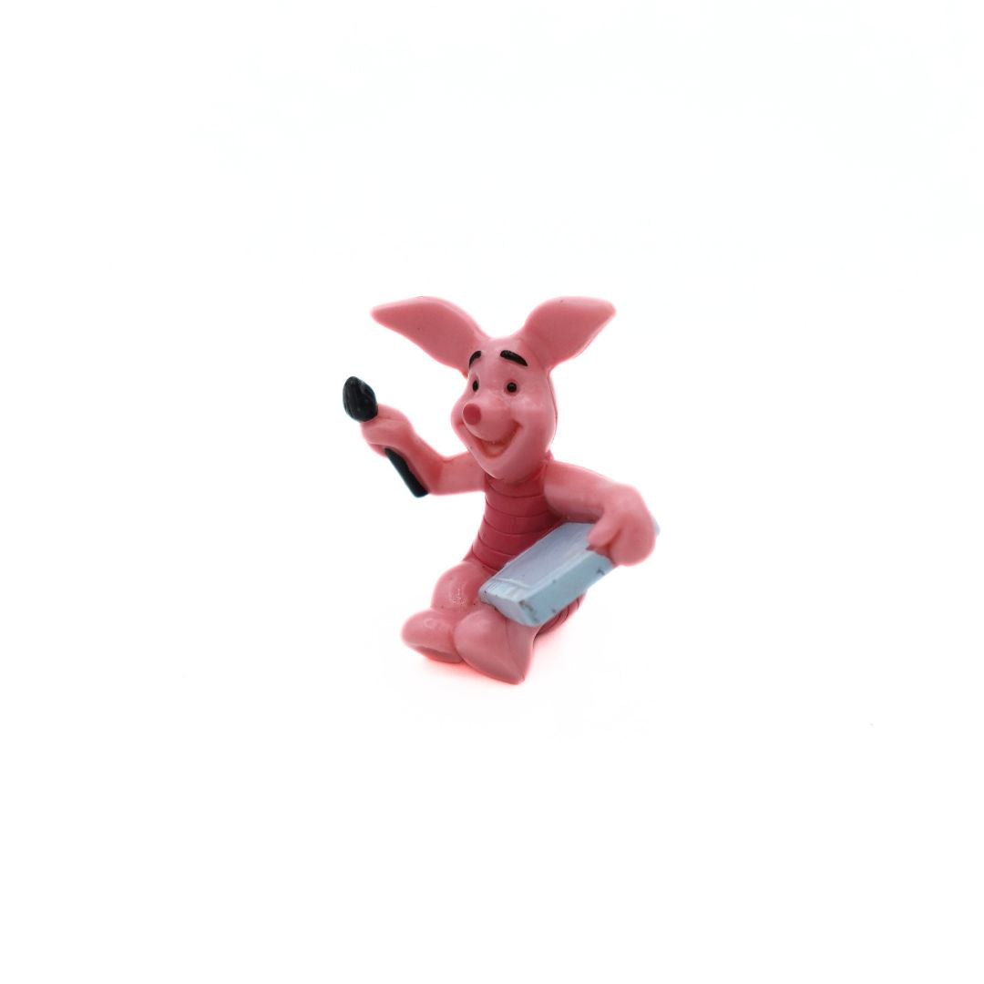 Pink Winnie the Pooh Piglet figurine with a grey canvas and black brush