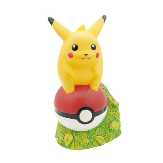 Pikachu figurine on a grassy base with a Poké Ball underneath on a white background