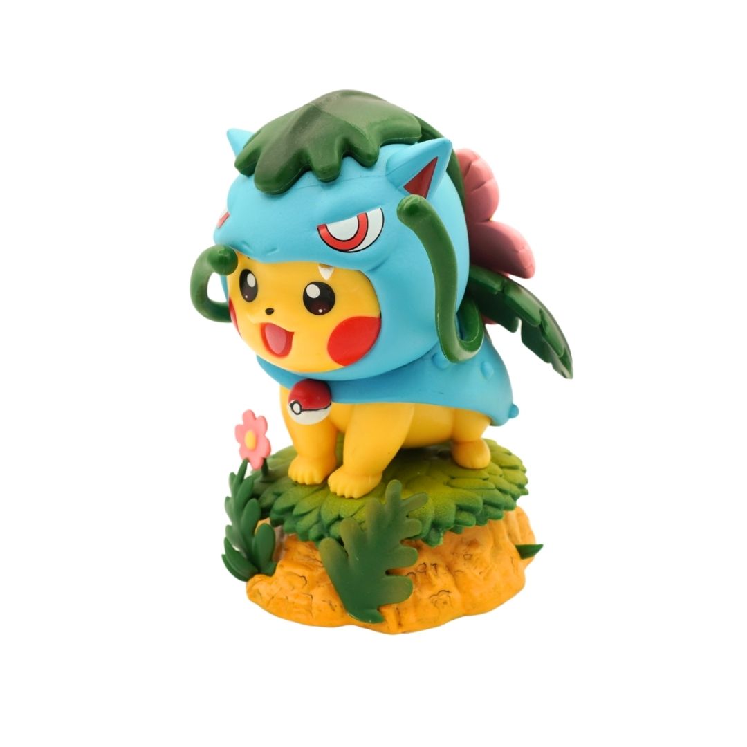 A collectible figurine of Pikachu from Pokémon, wearing a blue leaf-themed hood and standing on a small grassy base with a flower and orange rock detail, isolated on a white background.