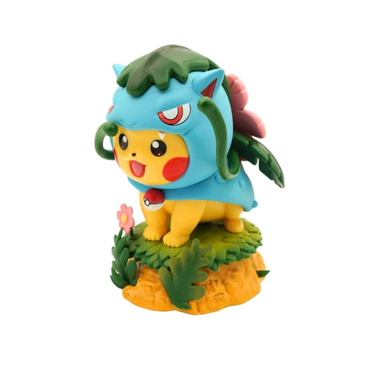 A collectible figurine of Pikachu from Pokémon, wearing a blue leaf-themed hood and standing on a small grassy base with a flower and orange rock detail, isolated on a white background.