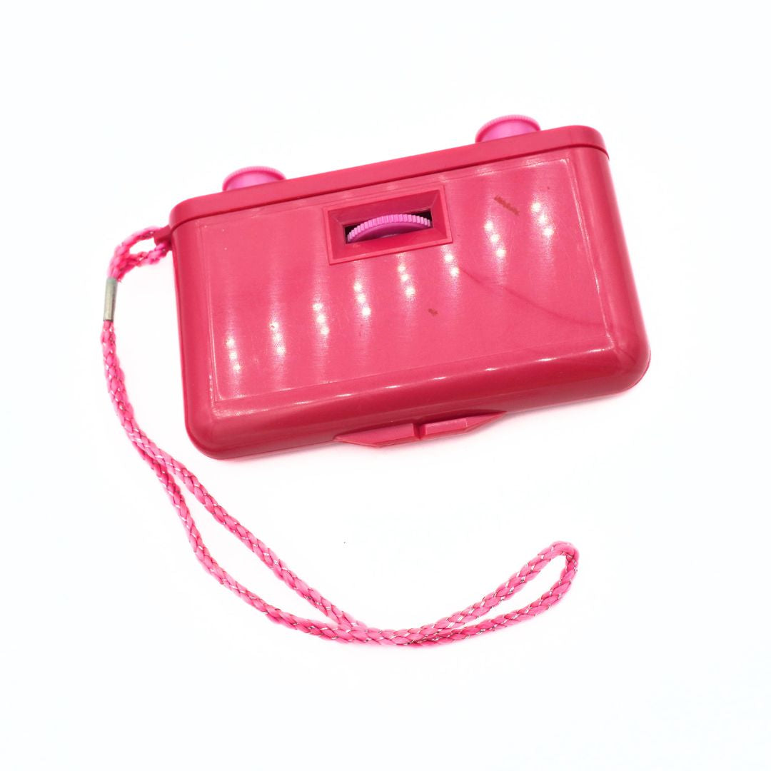 A bright pink plastic toy with a matching pink braided wrist strap, photographed on a plain white background.