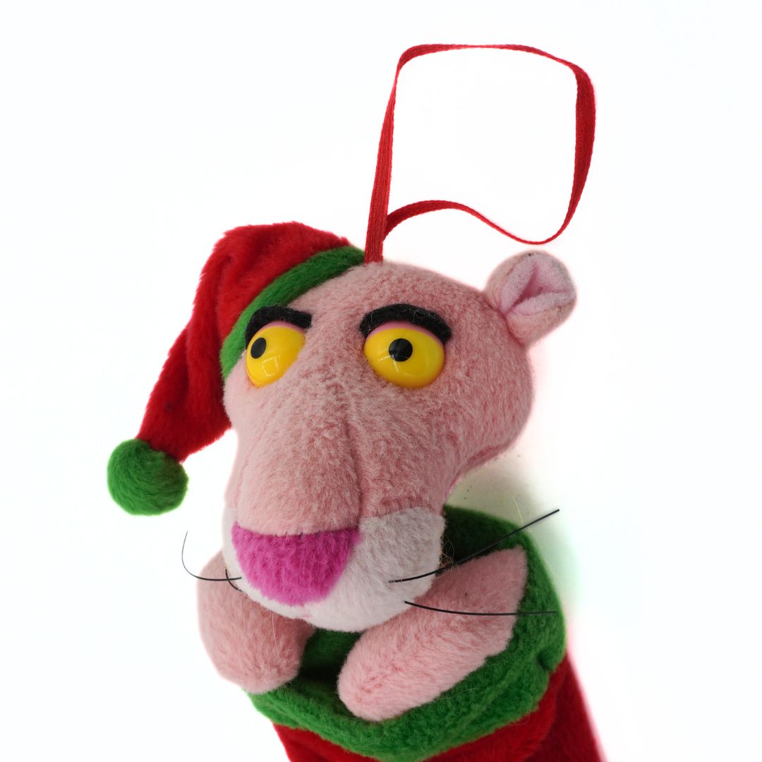 Plush toy resembling a pink panther character with a red hat on a white background