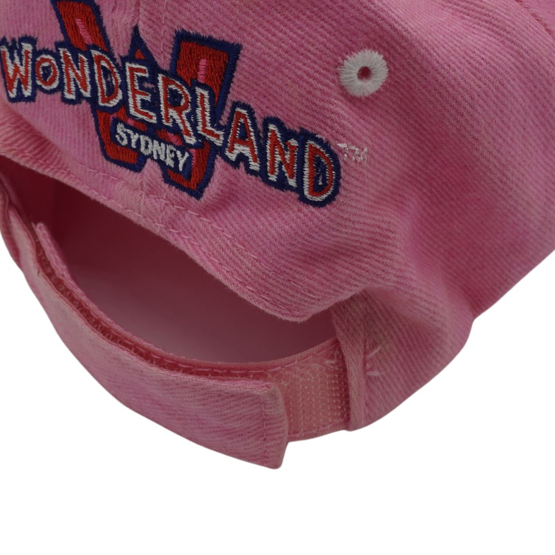 Close-up of a pink baseball cap showing the embroidered 'WONDERLAND SYDNEY' logo on the front panel and the adjustable hook-and-loop strap closure.