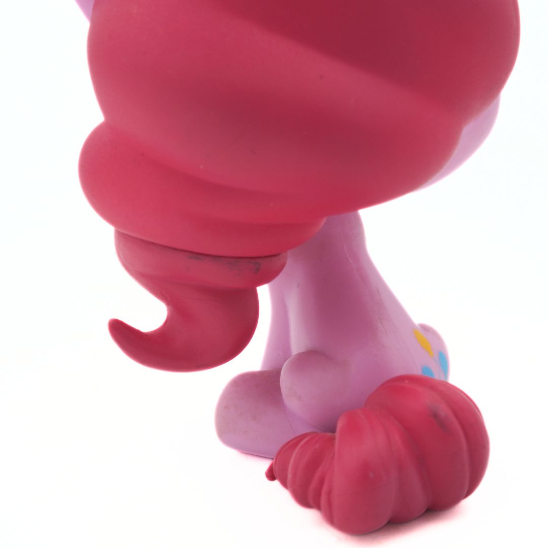 Close-up of a pink toy figure with red feet on a white background