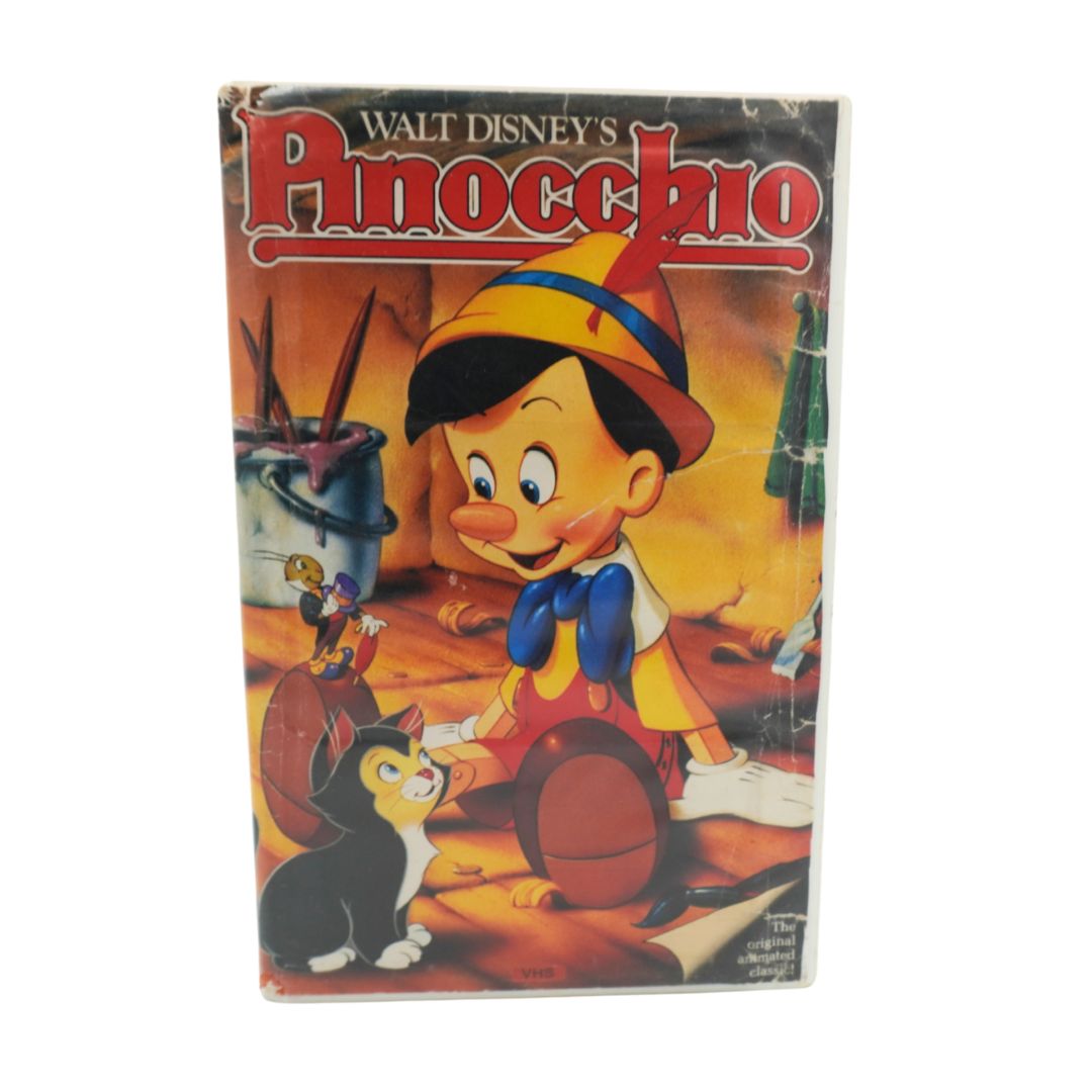 A vintage Walt Disney's Pinocchio VHS tape shown upright against a plain white background. The cover features the classic illustrated Pinocchio character with his signature yellow hat, red nose, blue bow tie, and black-and-white cat, with the title 'Walt Disney's Pinocchio' in large red letters at the top.
